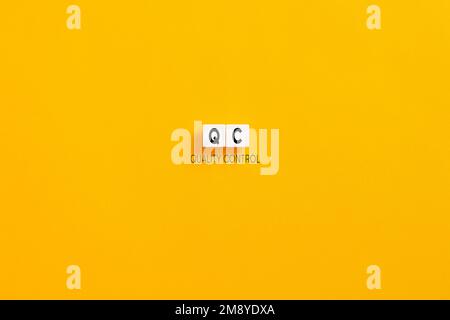 Weiße Buchstabenblöcke auf gelbem Hintergrund mit der Abkürzung QC Quality control. Qualitätskonzept für Produktion, Fertigung und Dienstleistungsbranche. Stockfoto