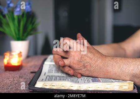Eine alte Frau liest die Bibel, die Hände sind dicht. Stockfoto