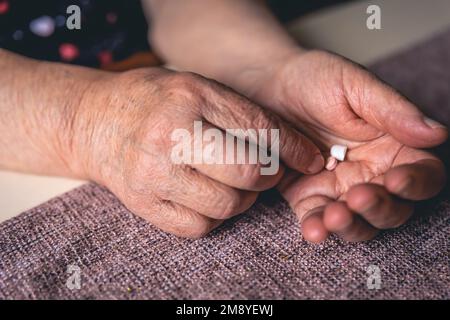 Pillen in den Händen einer alten Frau, Nahaufnahme. Stockfoto