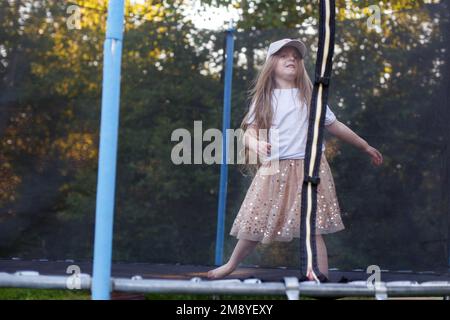 Ein kleines Mädchen, das auf dem Trampolin im Garten gesprungen ist Stockfoto