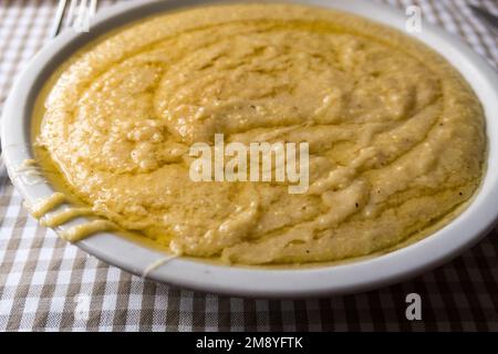 Ein Blick aus der Nähe auf eine Portion Polenta concia, eine traditionelle Mahlzeit, die in der Alpenregion Italiens serviert wird Stockfoto