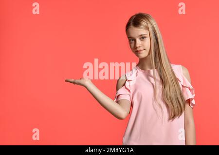 Studioporträt einer hübschen blonden Teenagerin in einem rosa T-Shirt mit pinkfarbenem Hintergrund. Stockfoto