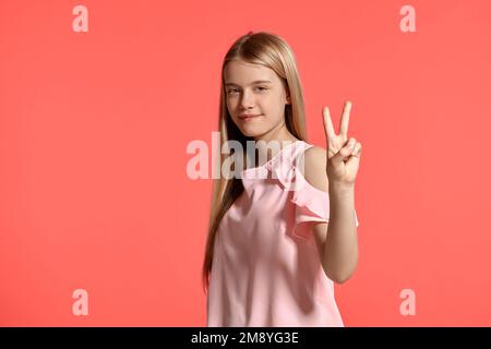 Studioporträt einer hübschen blonden Teenagerin in einem rosa T-Shirt mit pinkfarbenem Hintergrund. Stockfoto