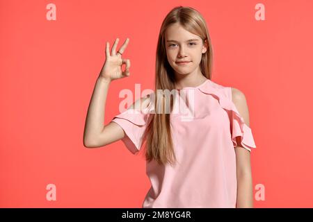 Studioporträt einer hübschen blonden Teenagerin in einem rosa T-Shirt mit pinkfarbenem Hintergrund. Stockfoto