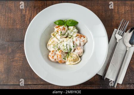 Verschiedene Arten von Pelmeni oder russischen Knödeln in weißer Platte auf Holzgrund Stockfoto
