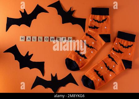 Orangefarbene Socken mit Fledermäusen. Kleidungskostüm für Halloween-Party. Fröhliche, bunte Socken, Draufsicht. Phrase in Holzbuchstaben. - Ja, Richtig. Stockfoto