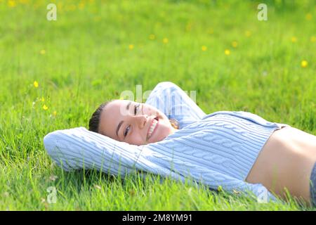 Eine lockere, glückliche Frau, die auf dem Rasen liegt in der Natur Stockfoto