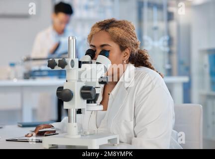 Es wartet immer etwas Aufregendes. Eine junge Laborarbeiterin analysiert Proben mit einem Mikroskop. Stockfoto