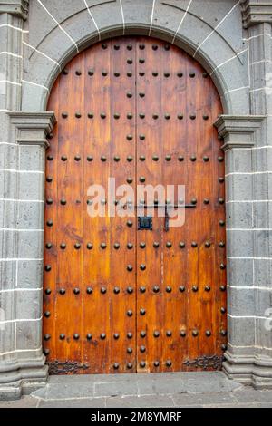 Alte, riesige Holztür in einer Steinwand einer Kirche. Stockfoto