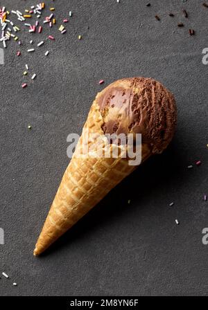 Karamell- und Schokoladeneis in Waffelform auf dunkelgrauem Hintergrund, Draufsicht Stockfoto
