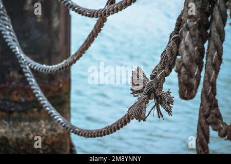 Knoten an einem alten Schiffsseil auf einem Steg über dem Wasser, Metapher für Kohäsion, Kopierraum, ausgewählter Fokus, schmale Schärfentiefe Stockfoto