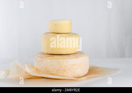 Ein Stapel verschiedener Käseköpfe, gestapelt in vertikaler Reihe auf dem Tisch. Mittelharte Käseköpfe auf Holzschneidebrett. Gesunde Bio-Ernährung Konz Stockfoto