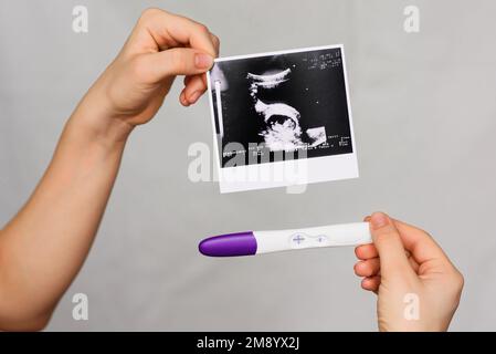 Ultraschallbild und positiver Schwangerschaftstest in der Hand eines Mädchen-Nahaufnahmen Stockfoto