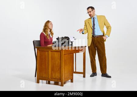 Geschäftsmann, der mit seiner persönlichen Hilfe spricht, weibliche Informationen zu schreiben. Professionelle Notizen zur klassischen Schreibmaschine machen. Geschäftskonzept Stockfoto