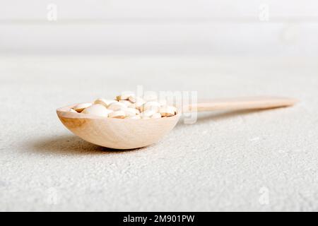 Haufen weißer Pillen auf farbigem Hintergrund. Tabletten auf einem Tisch verstreut. Haufen roter weicher Gelatinekapsel. Vitamine und Nahrungsergänzungsmittel Konzept. Stockfoto