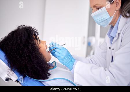 Die Zunge dreht sich immer zu dem schmerzenden Zahn. Eine junge Patientin, die ihre Zähne beim Zahnarzt untersuchen lässt. Stockfoto