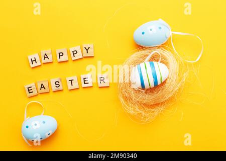 Farbenfrohe handgefertigte Eier im Nest auf orangefarbenem Hintergrund mit Kopierbereich. Stockfoto