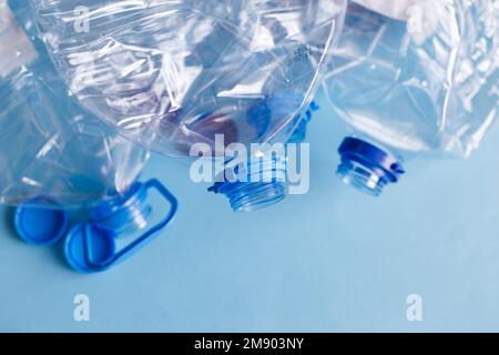 Viele leere Plastikflaschen auf blauem Hintergrund. Abfall- und Verschmutzungskonzept. Stockfoto