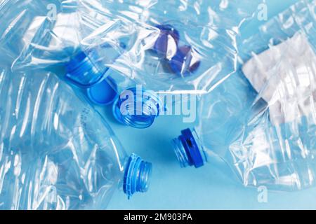 Viele leere Plastikflaschen auf blauem Hintergrund. Abfall- und Verschmutzungskonzept. Stockfoto