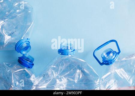 Viele leere Plastikflaschen auf blauem Hintergrund. Abfall- und Verschmutzungskonzept. Stockfoto