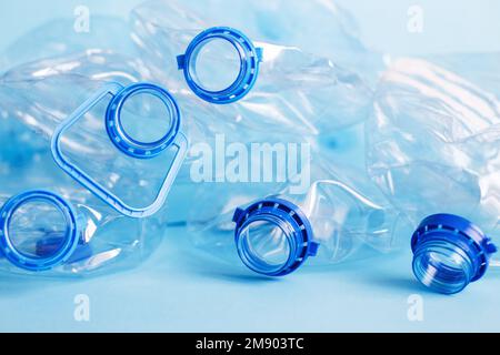 Viele leere Plastikflaschen auf blauem Hintergrund. Abfall- und Verschmutzungskonzept. Stockfoto