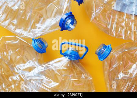 Viele leere, verdorbene Flaschen aus Plastik auf gelbem Hintergrund. Abfall- und Verschmutzungskonzept. Stockfoto