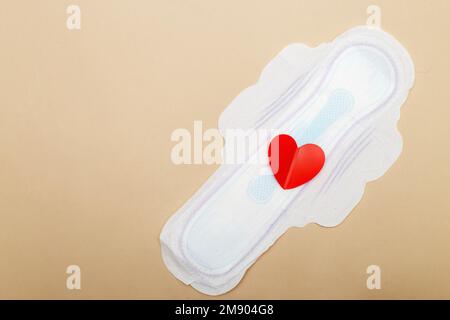 Damenpolster auf beigefarbenem Hintergrund mit rotem Herzen. Stockfoto
