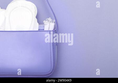 Tampons, hygienische Unterhosen, weibliche Hygienepads in einer Kosmetiktasche für Frauen auf lila Hintergrund. Hygiene und Frauengesundheitskonzept Stockfoto