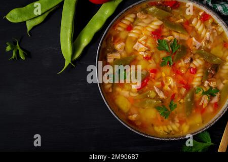 Minestrone, italienische Gemüsesuppe mit Pasta auf schwarzem Tisch. Draufsicht, flach liegend, Kopierbereich Stockfoto