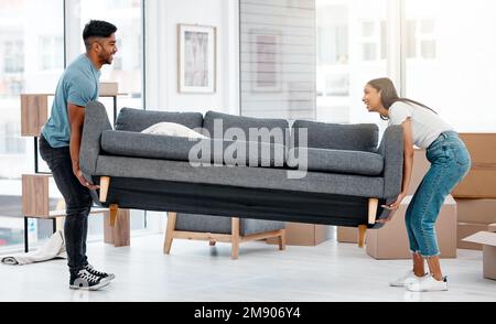 Wohin soll das gehen? Die volle Länge eines jungen Paares, das zu Hause sein Sofa bewegt. Stockfoto