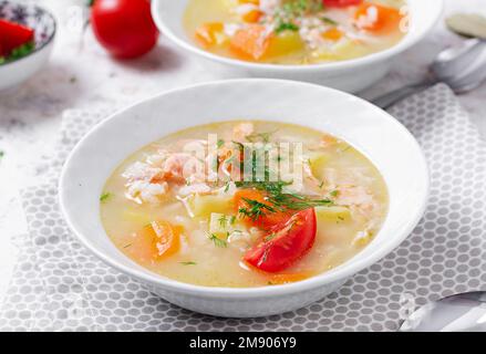 Fischsuppe mit Lachs, Gemüse und Reis in einer weißen Schüssel. Stockfoto