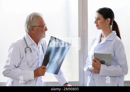 Ärzte des medizinischen Chirurgen schauen sich den Röntgenfilm an und besprechen die Behandlung vor der Operation im Krankenhaus. Stockfoto
