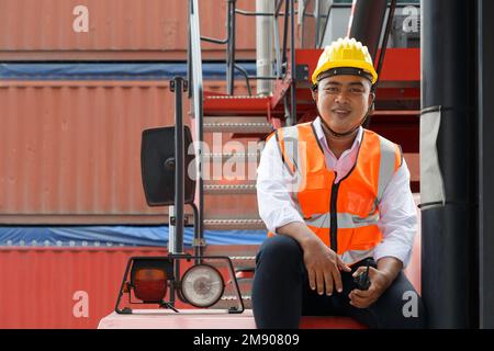 ein asiatischer Arbeiter, der auf der Treppe sitzt, um sich auszuruhen, und nach Abschluss der Fracht in der Hafen- oder Lagerfabrik eine Pause einlegt. Branche und logis Stockfoto