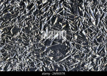 Silberne zerknitterte Aluminiumfolie flacher Hintergrund und flache Struktur. Glänzende Oberfläche. Stockfoto