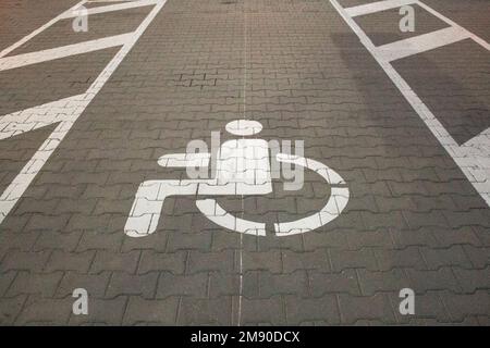 Weißes Zeichen eines Parkplatzes für Behinderte auf einer Straße Stockfoto