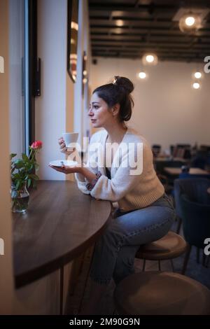 Junge Frau, die im Café Kaffee trinkt. Stockfoto