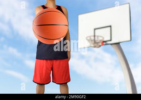 Ein Spieler hält einen Basketball im Stadion im Freien Stockfoto
