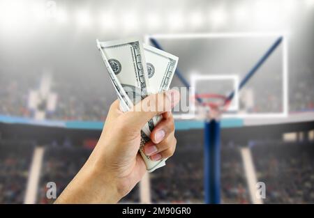 Nahaufnahme eines Mannes, der ein Bündel Hundert-Dollar-Scheine zerquetscht, um Geld mit Wetten im Basketball zu bekommen Stockfoto