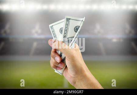 Nahaufnahme eines Mannes, der ein Bündel Hundert-Dollar-Scheine zerquetscht, um mit Wetten im Fußball Geld zu bekommen Stockfoto