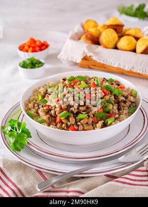 Pflanzenbasierte Version des US-amerikanischen Südgericht Hoppin John mit schwarzen Augenerbsen, braunem Reis, grünen Zwiebeln, rotem Paprika und Maisbrot-Muffins Stockfoto