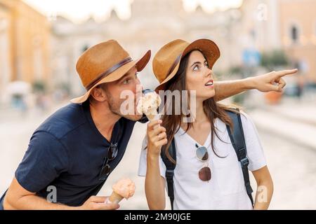 Glückliches Paar, das in Rom, Italien, Eis isst. Wunderschönes, helles Eis mit verschiedenen Geschmacksrichtungen in den Händen eines Paares Stockfoto