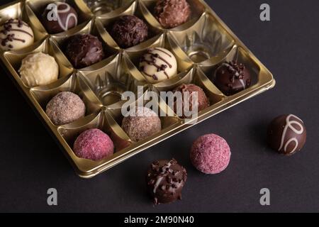 Fotobonbons, die in einem Paket neben dem Paket liegen, sind ein paar Süßigkeiten auf schwarzem Hintergrund Stockfoto