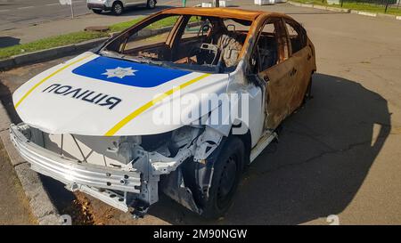 Abgebrannter Polizeiwagen. Vandalismus, verbranntes Auto. Ein Auto nach dem Feuer. Automatischer Papierkorb. Zerstörter Streifenwagen der ukrainischen Nationalpolizei. Übersetzung - Stockfoto