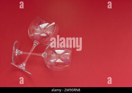 Leere Weingläser liegen auf rotem Hintergrund. Valentinstag-Konzept. Stockfoto