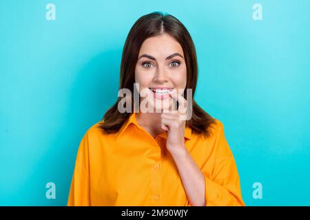 Foto einer hübschen, sprachlosen Frau mit glatter Frisur tragen Sie ein gelbes Hemd, Fingernägel, die isoliert auf einen blauen Hintergrund starrt Stockfoto