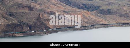 Großer und langer Güterzug, der sich durch den Fraser Canyon, die Berge von British Colombia und Kanada schlängelt Stockfoto