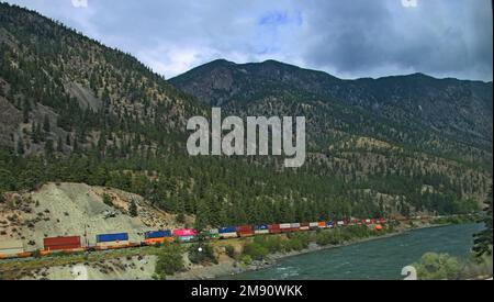 Großer und langer Güterzug, der sich durch den Fraser Canyon, die Berge von British Colombia und Kanada schlängelt Stockfoto