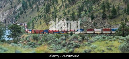 Großer und langer Güterzug, der sich durch den Fraser Canyon, die Berge von British Colombia und Kanada schlängelt Stockfoto