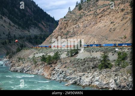 Großer und langer Güterzug, der sich durch den Fraser Canyon, die Berge von British Colombia und Kanada schlängelt Stockfoto