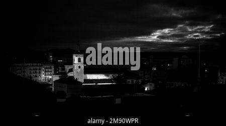 Schwarzes Bild mit Blick von oben auf eine beleuchtete Kirche San Millán bei Nacht in Segovia, Spanien. Stockfoto